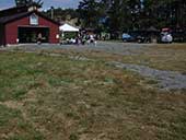 A field foremost; a red barn beside a popup tent behind.