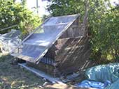 A wooden box is covered by a plastic sheet mounted at an angle above it.