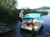 Man standing beside boat on a lakeside.