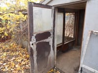 An open door shows the interior of an empty shed.