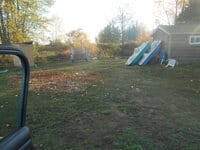 Two paddleboats lean vertically against a shed in an open grassy field.