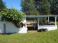 An open-air wood structure covering a table and lawnchair.