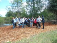 St. Michael's School students post for a group photo in front of a small lake on woodchips.